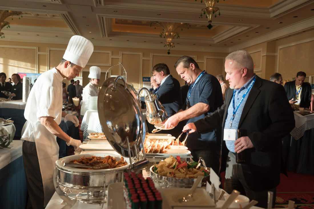 Chef in whites serving conference attendees at a buffet during a networking lunch
