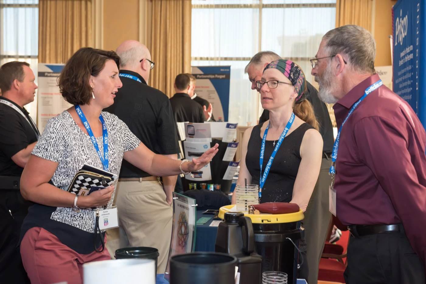 Attendees with lanyards talking in small groups during a coffee break
