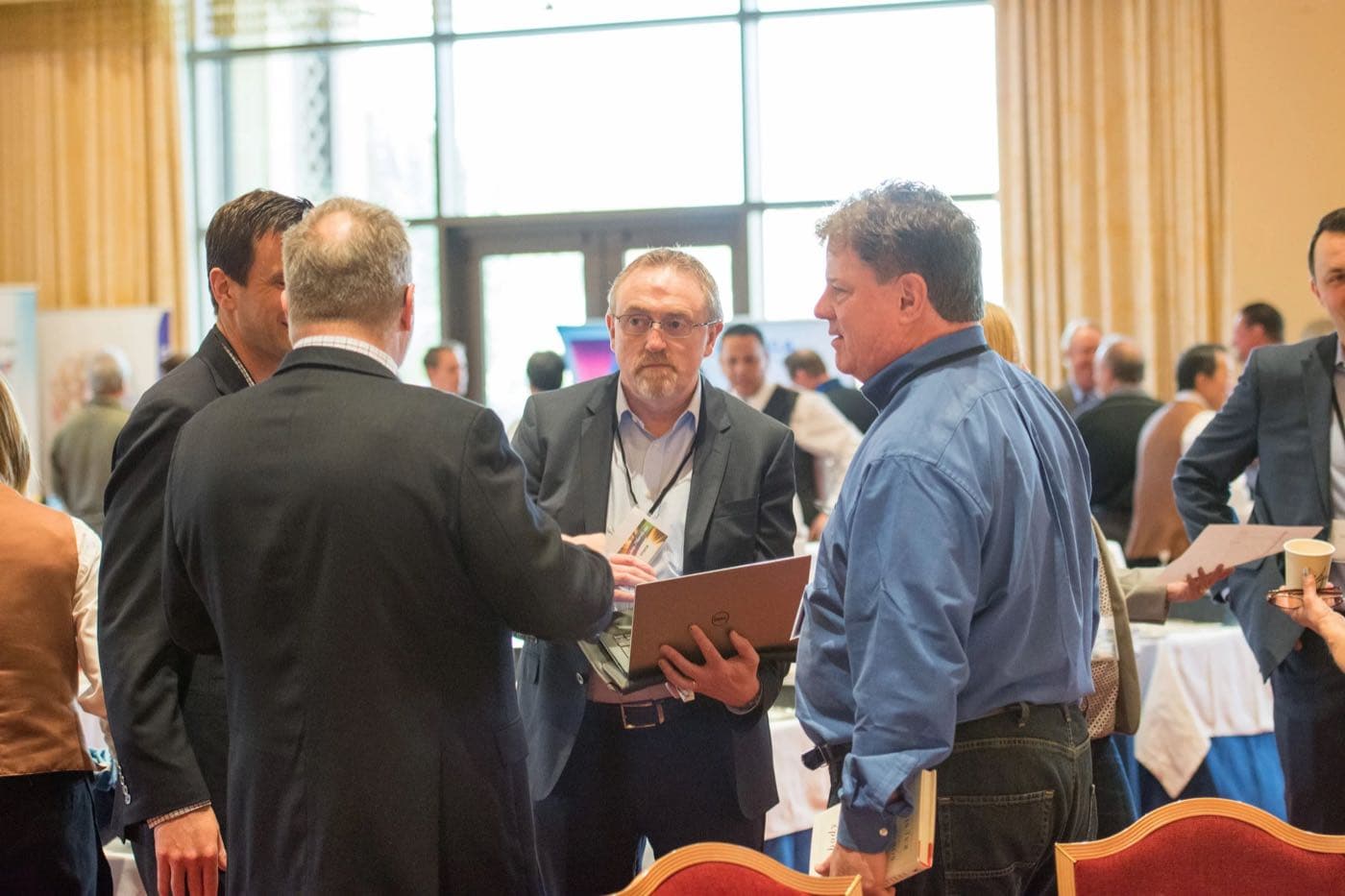 Group of attendees gathered around a laptop in a bright conference foyer