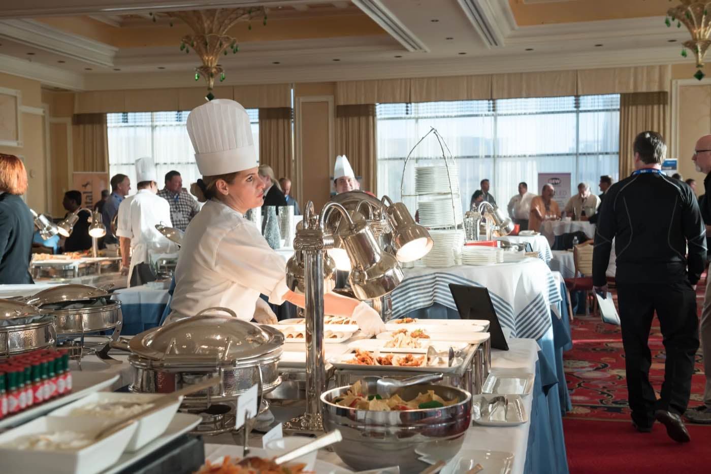 Chef at a buffet station in a daylight ballroom with attendees in the background