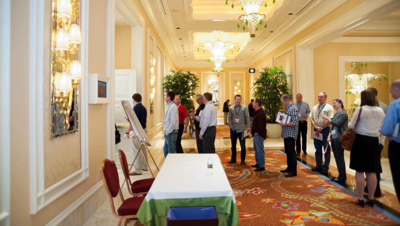 Attendees mingling and talking in an ornate hotel corridor between sessions
