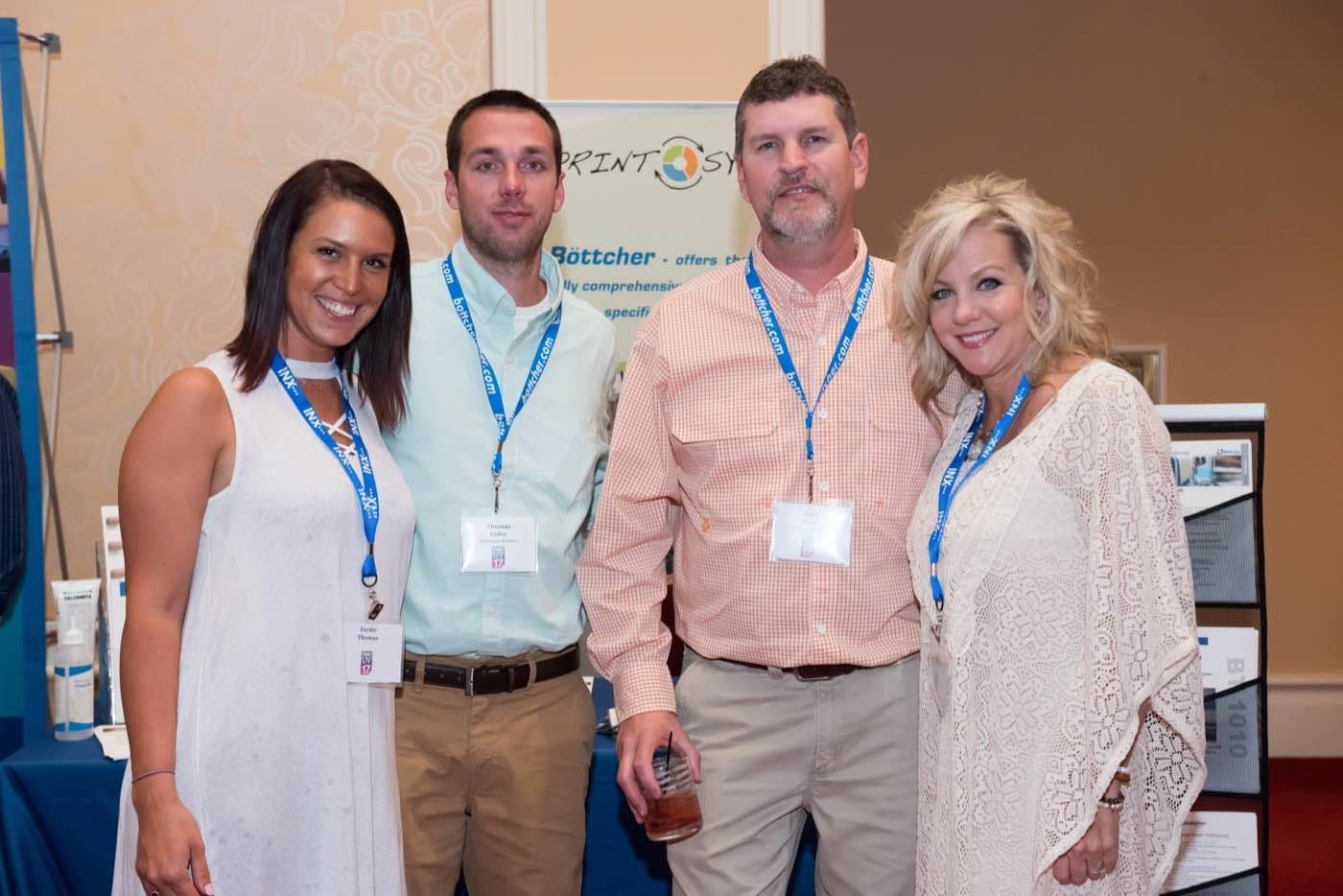 Four attendees posing together in front of a sponsor display