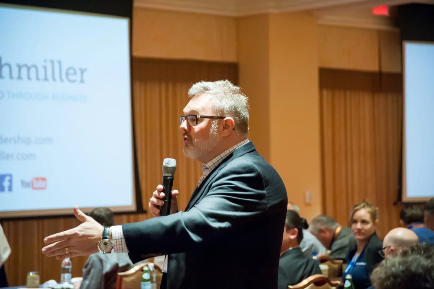 Speaker holding a microphone and gesturing to the audience during a session