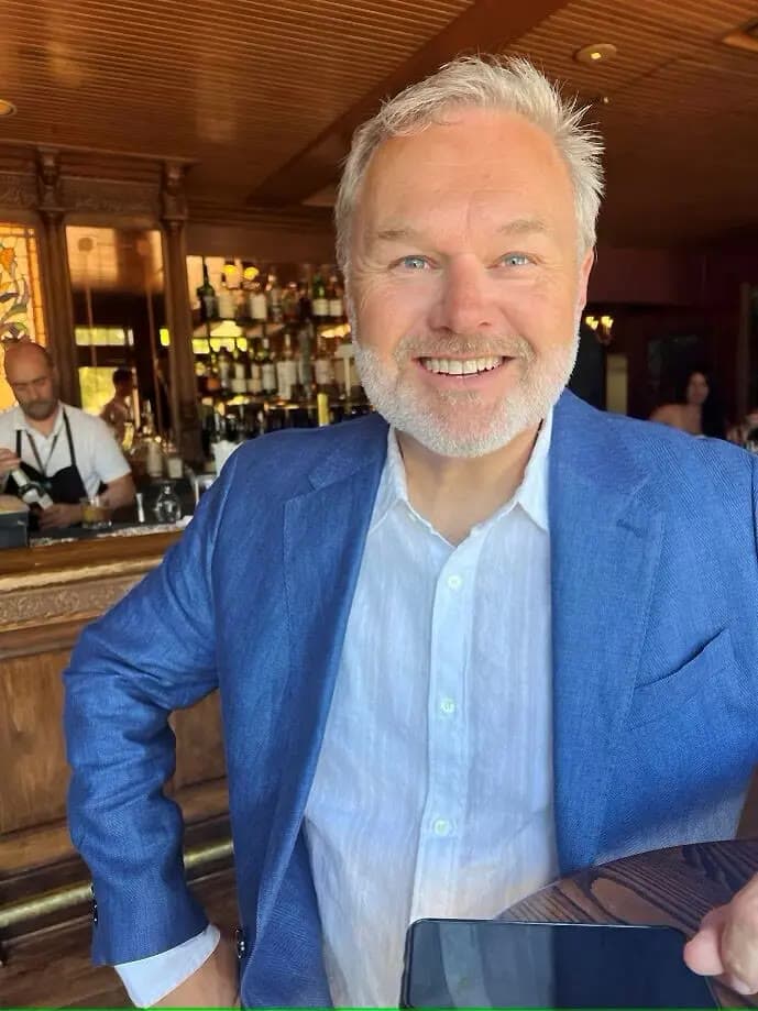 Hans Ulland smiling in a blue blazer over an open-collar white shirt